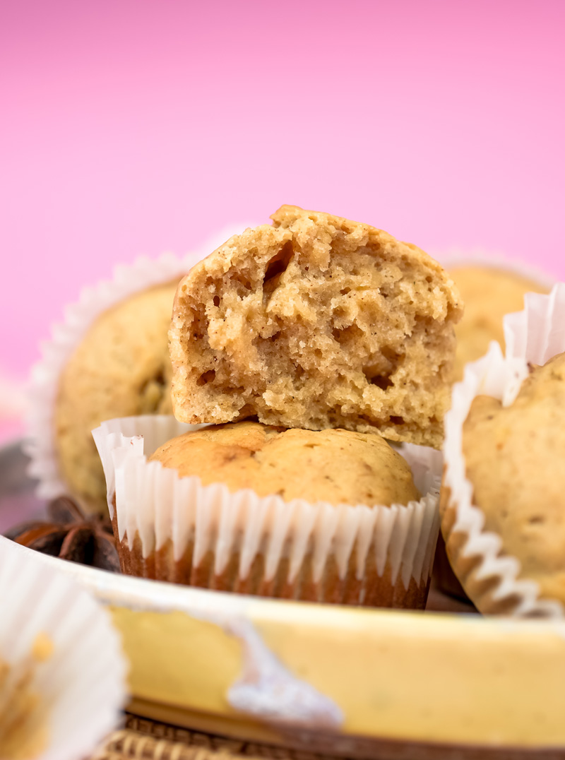 Broken mini banana muffin showing moist interior texture on pink background