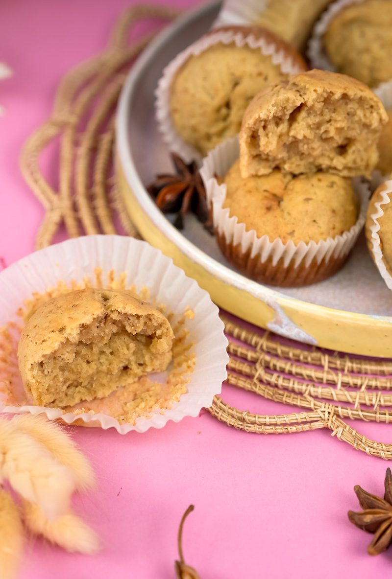 Mini banana muffins with bite taken out showing fluffy texture on decorative plate