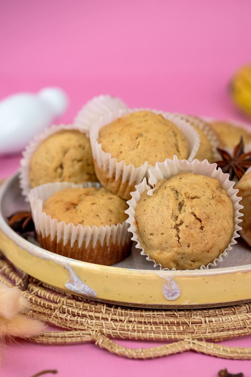 Mini banana muffins with soft texture on yellow ceramic plate against pink background