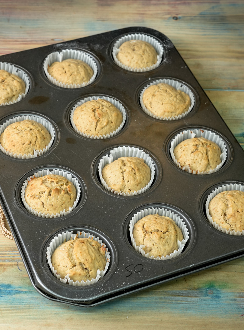 Freshly baked mini banana muffins in muffin tin with paper liners