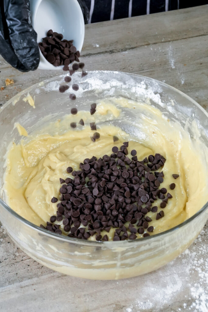 Adding chocolate chips to banana muffin batter