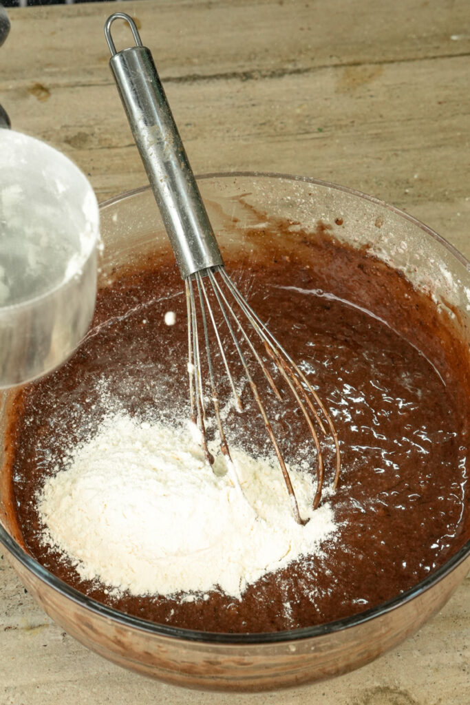 Adding flour to chocolate muffin mixture with whisk
