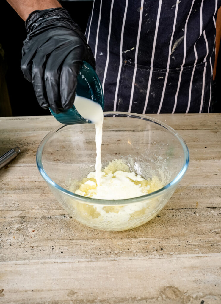 Pouring milk into the coffee cake muffin batter.