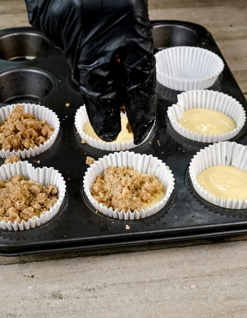 Adding streusel topping to coffee cake muffins.