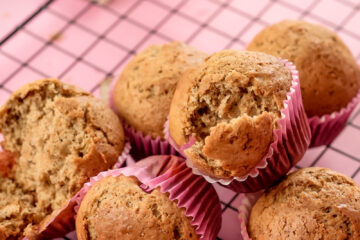 Banana muffins with one split open showing interior crumb