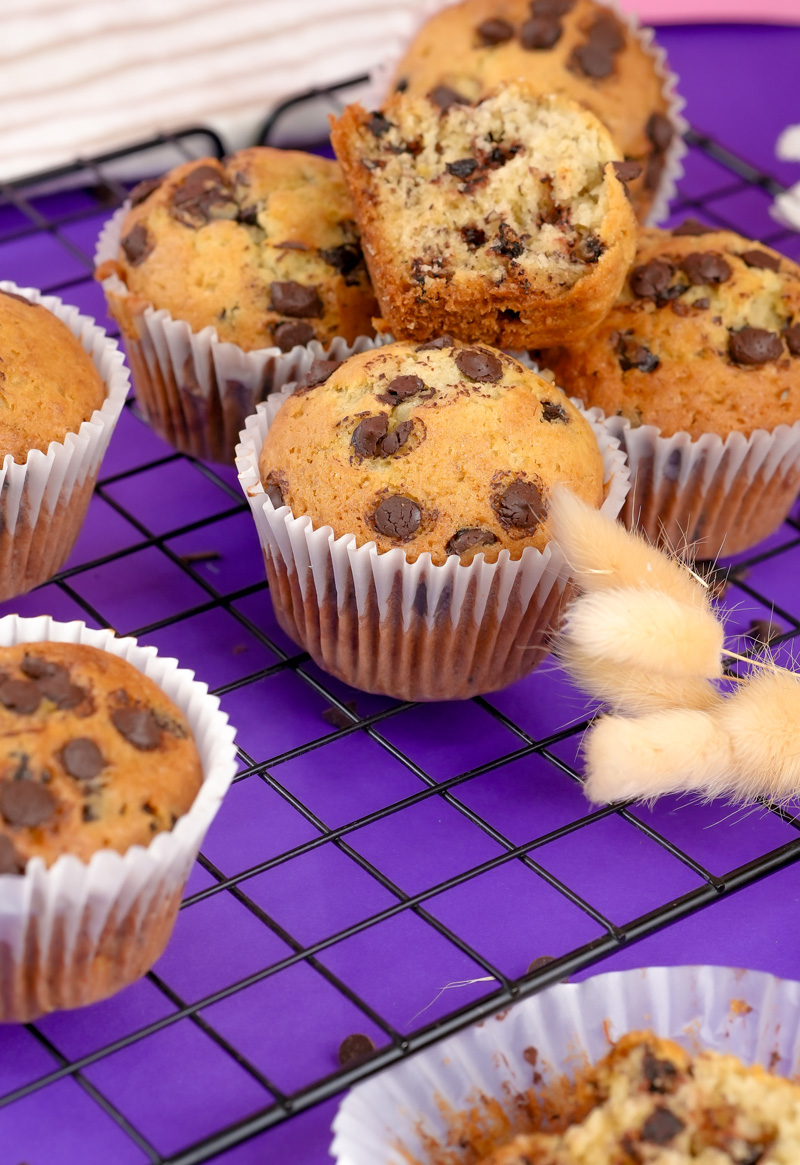 Broken banana protein muffin showing texture, surrounded by more muffins.