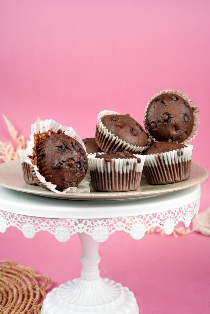 Chocolate chip muffins with one opened showing moist interior