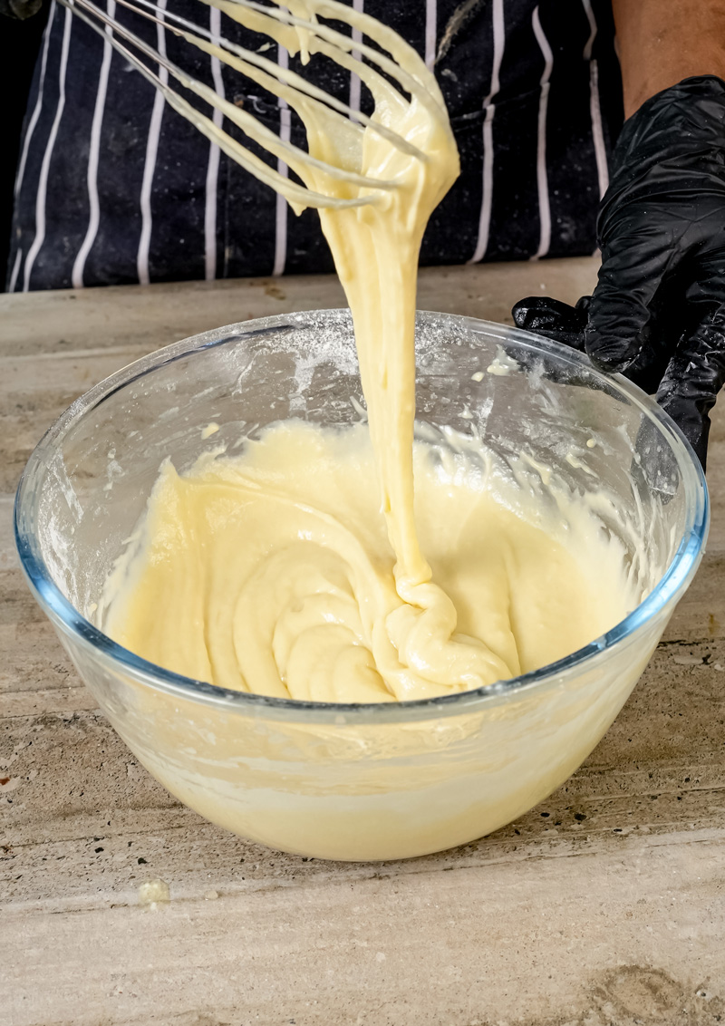 Coffee cake muffin batter dripping from a whisk.
