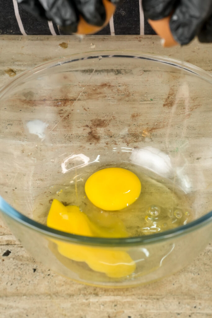 Cracking egg into bowl for homemade pistachio muffins
