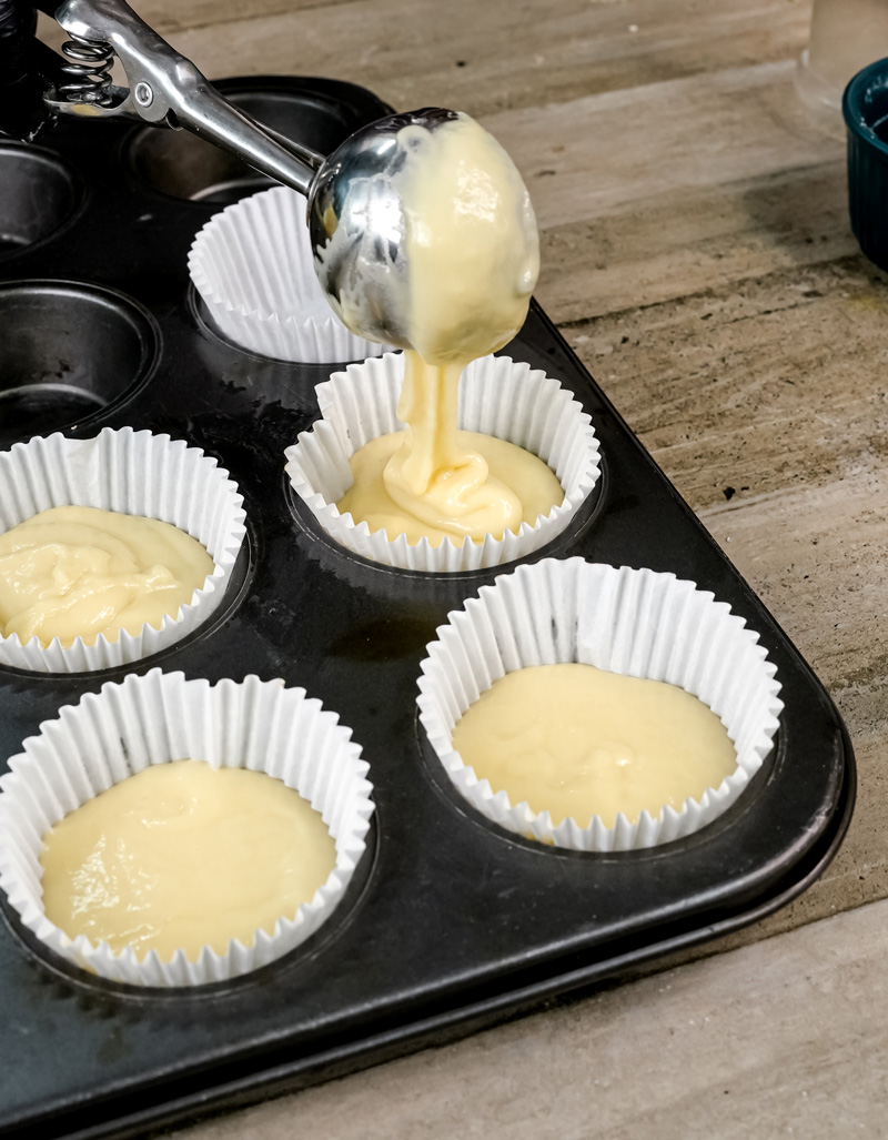 Filling muffin liners with coffee cake batter.