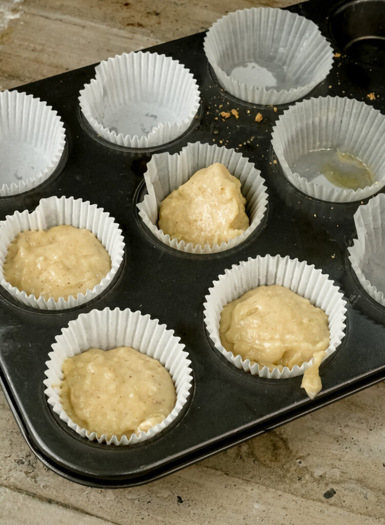 Filling muffin tin with oatmeal batter in paper liners