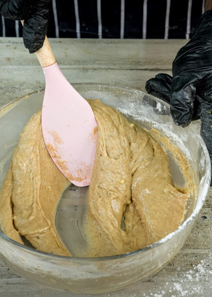 Folding banana muffin batter with pink spatula