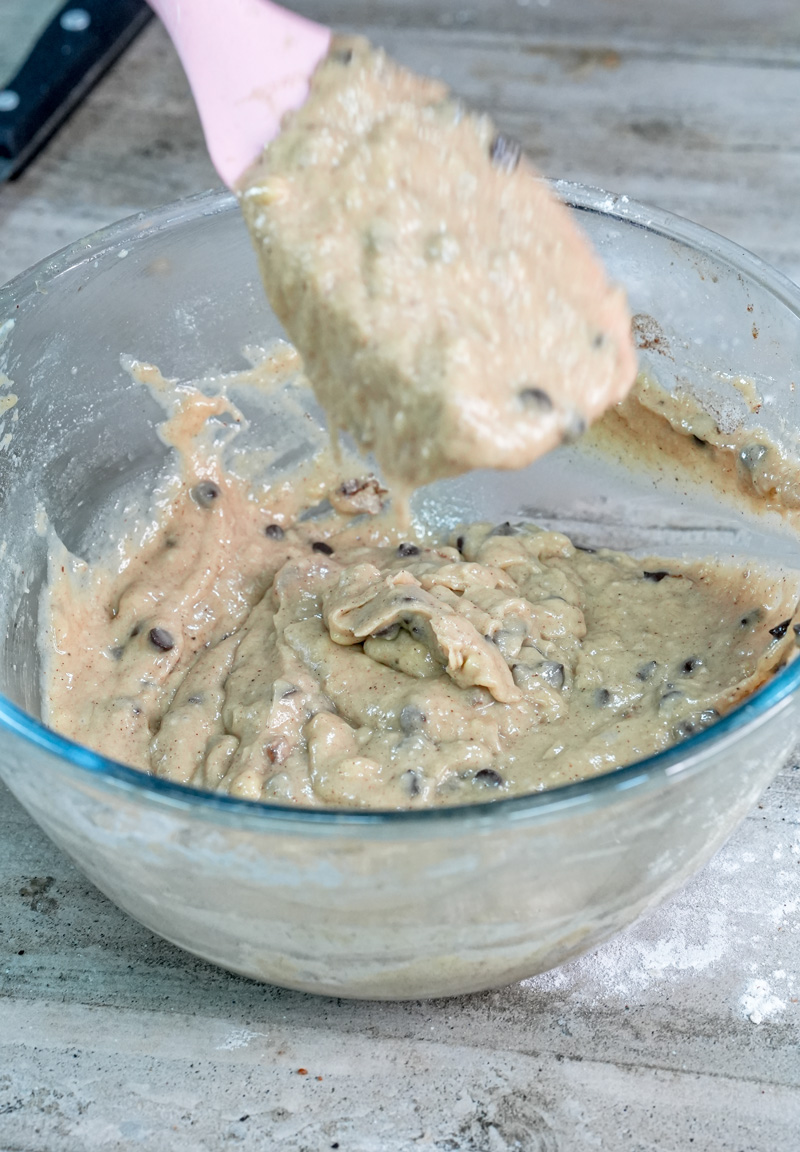 Folding banana protein muffin batter in a glass bowl.