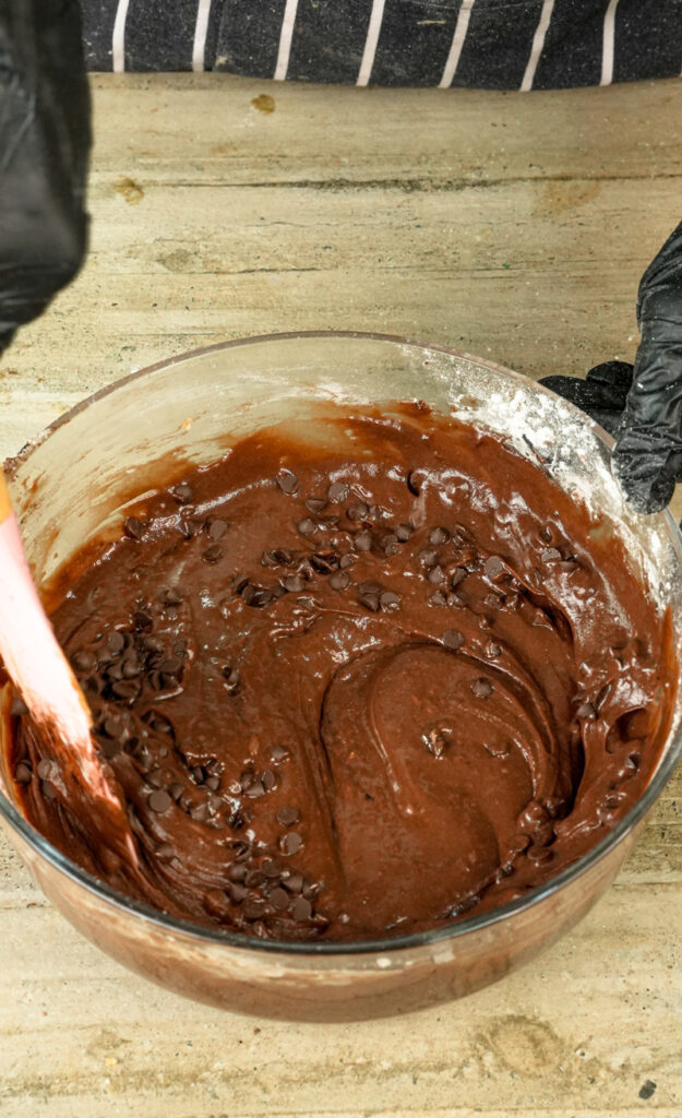 Folding chocolate chips into muffin batter with wooden spoon