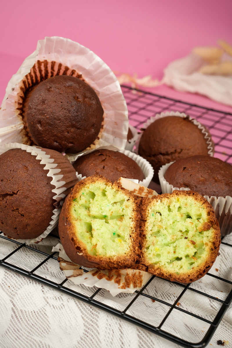 Homemade chocolate-coated pistachio muffins against pink background