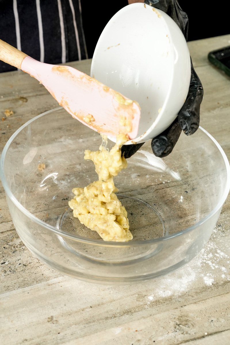 Mashed banana mixture being transferred to mixing bowl