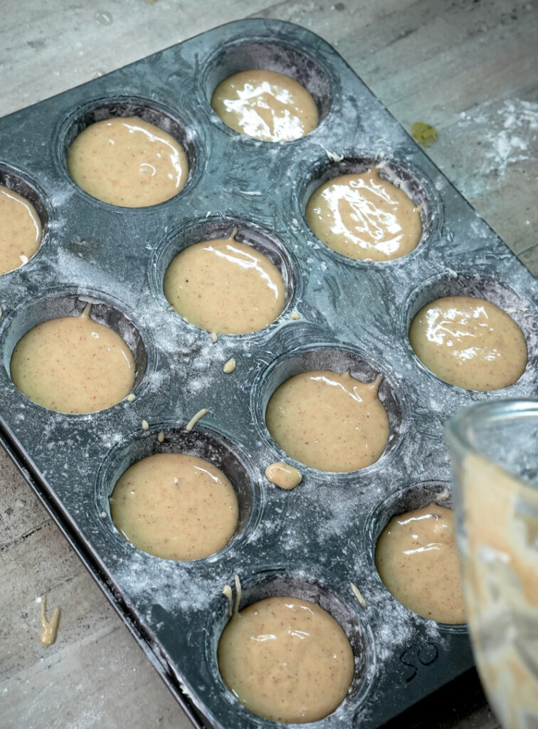 Muffin tin filled with cinnamon muffin batter, ready for baking
