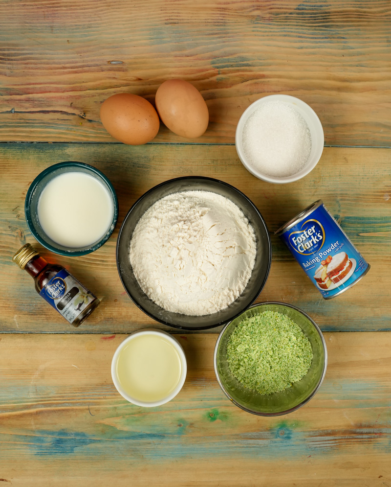 Pistachio muffin ingredients on wooden surface including eggs, flour, sugar and pistachio powder