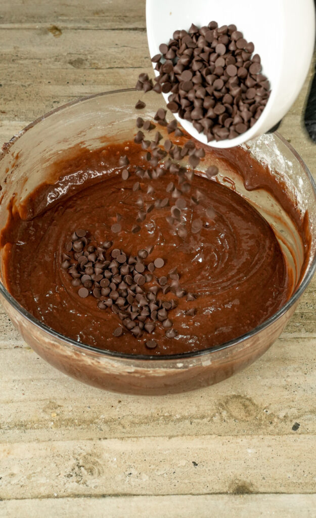 Pouring chocolate chips into double chocolate muffin batter