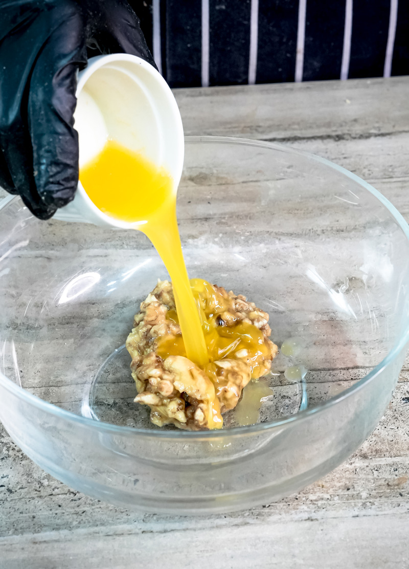Pouring honey into mashed banana mixture with walnuts
