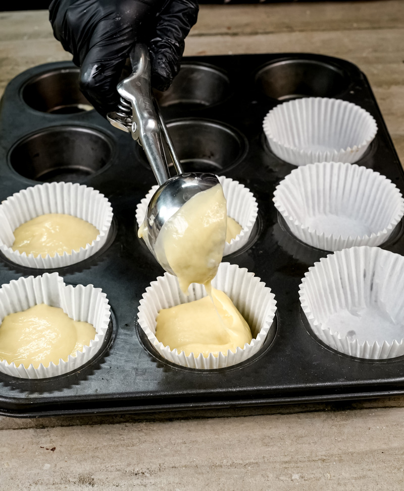 Scooping coffee cake muffin batter into liners.