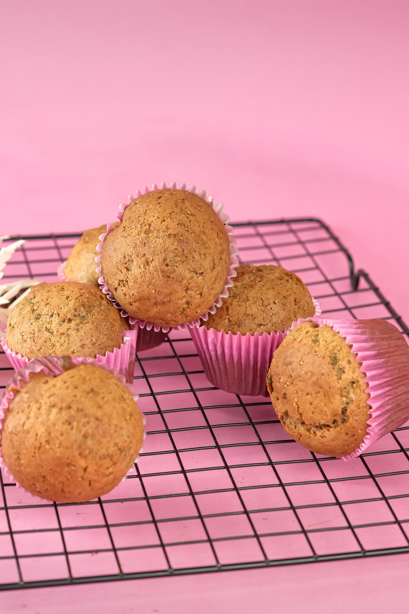 Freshly baked banana muffins in pink liners on cooling rack