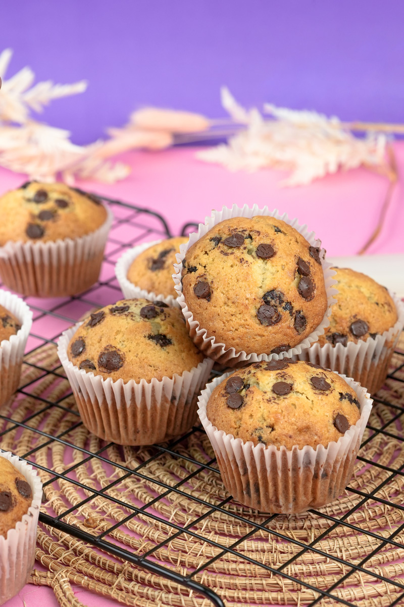 Freshly baked banana protein muffins with chocolate chips on a cooling rack.