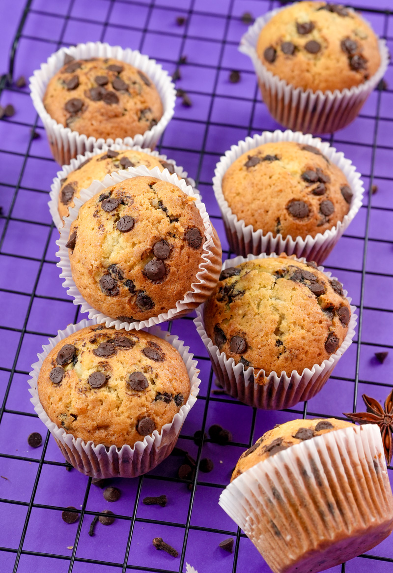 Top view of banana protein chocolate chip muffins on a purple background.