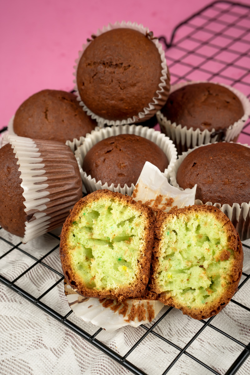Pistachio muffins with one cut open on wire rack