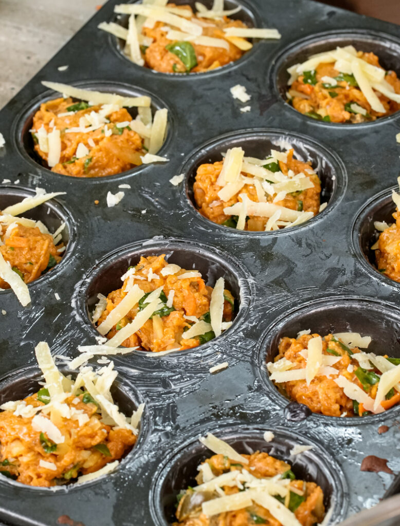 Adding final cheese topping to pizza muffins in muffin tin