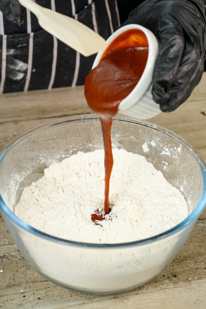 Adding pizza sauce to flour mixture in glass bowl