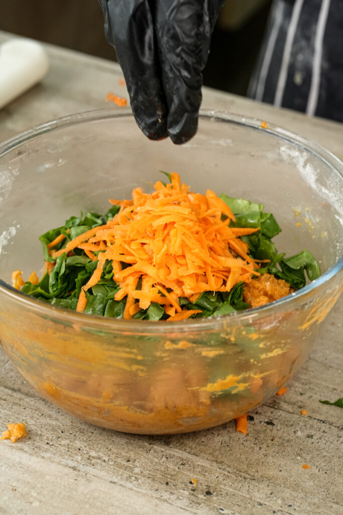Adding shredded cheddar cheese to pizza muffin mixture