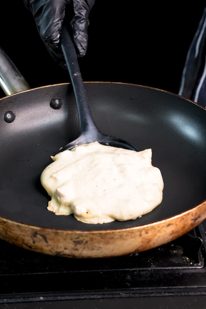 Apple cinnamon pancake batter cooking in non-stick pan