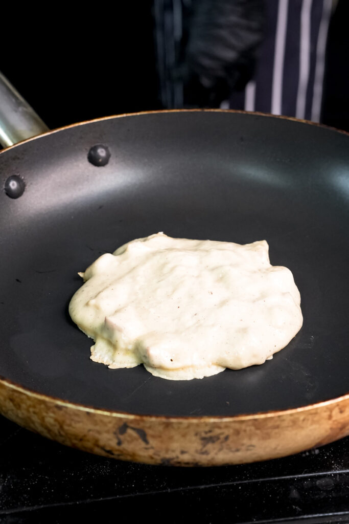 Apple cinnamon pancake cooking in non-stick pan
