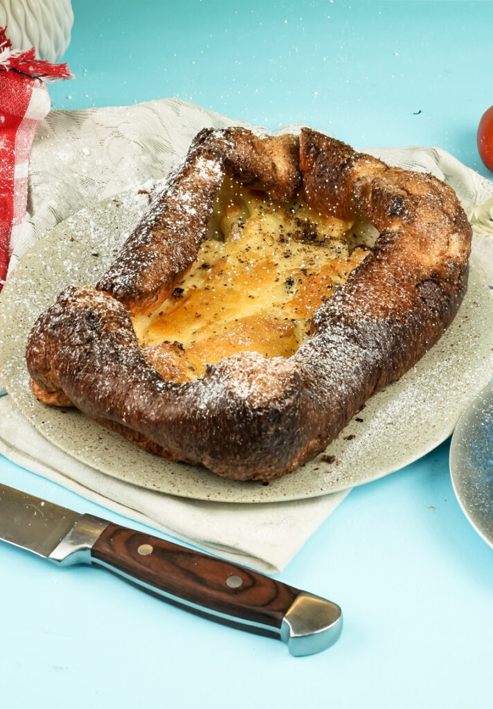 Baked German pancake dusted with powdered sugar in baking dish