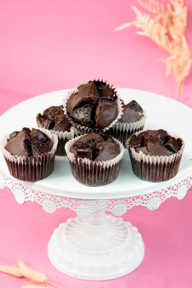 Chocolate chip peanut butter banana muffins on white pedestal