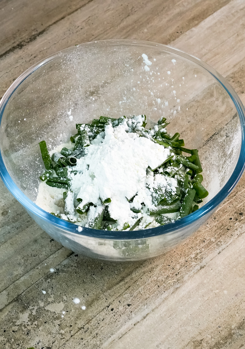 Chopped scallions mixed with flour in glass bowl