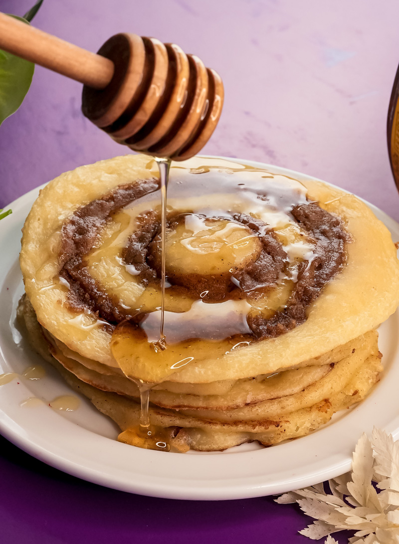 Adding honey topping to homemade cinnamon roll pancakes