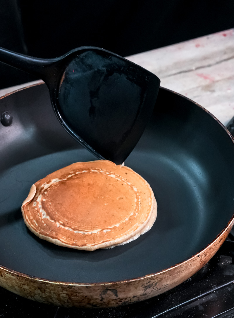 Cooking peanut butter pancake on non-stick pan with spatula