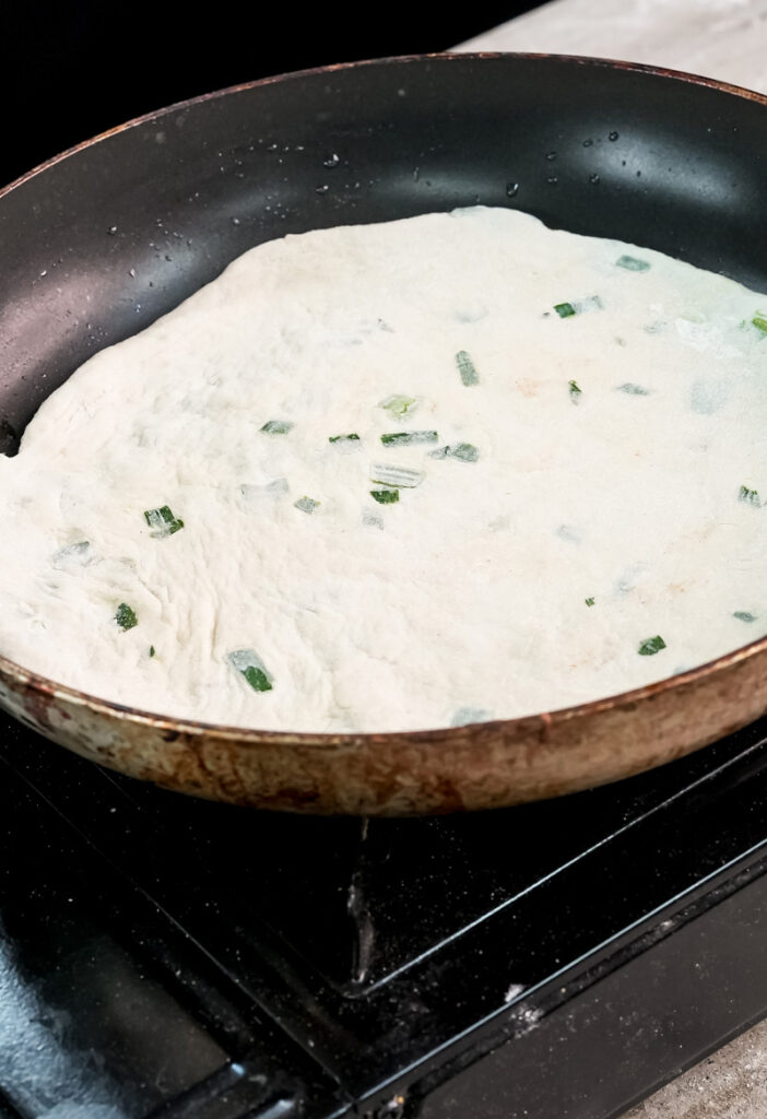 Cooking scallion pancake in non-stick pan until golden