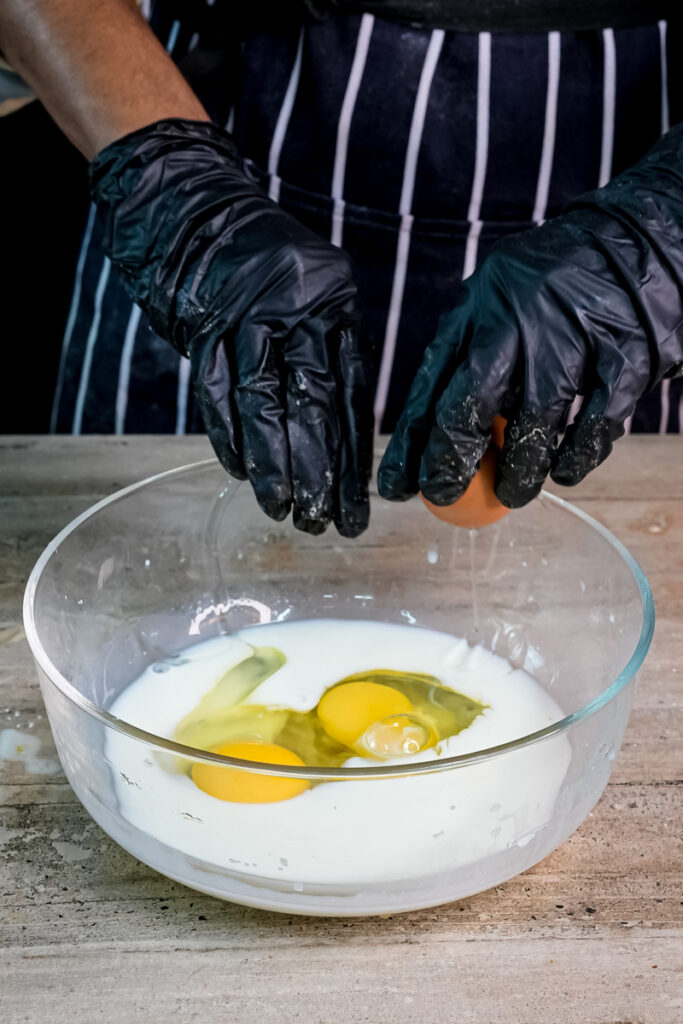 Cracking fresh eggs into milk for homemade silver dollar pancakes
