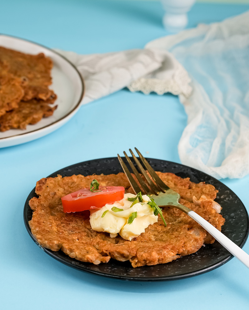 Crispy German potato pancake plated with fresh herbs and tomato