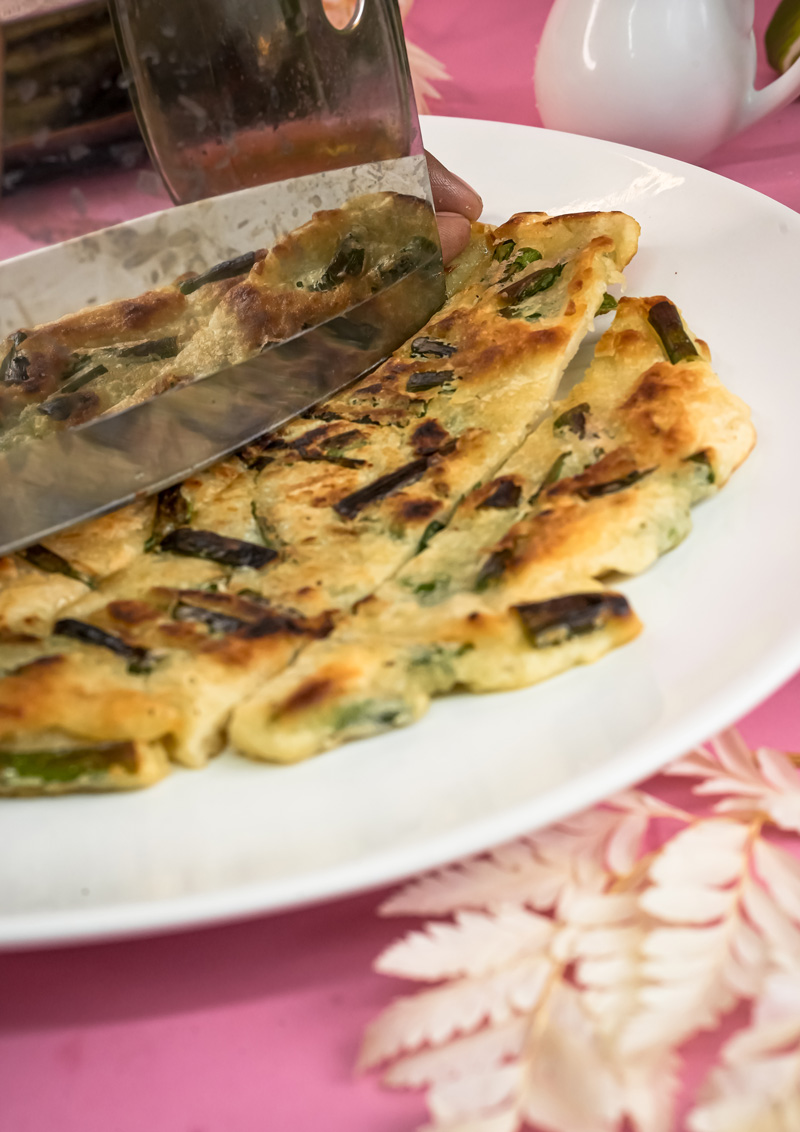 Cutting cooked Korean pancake with kitchen scissors