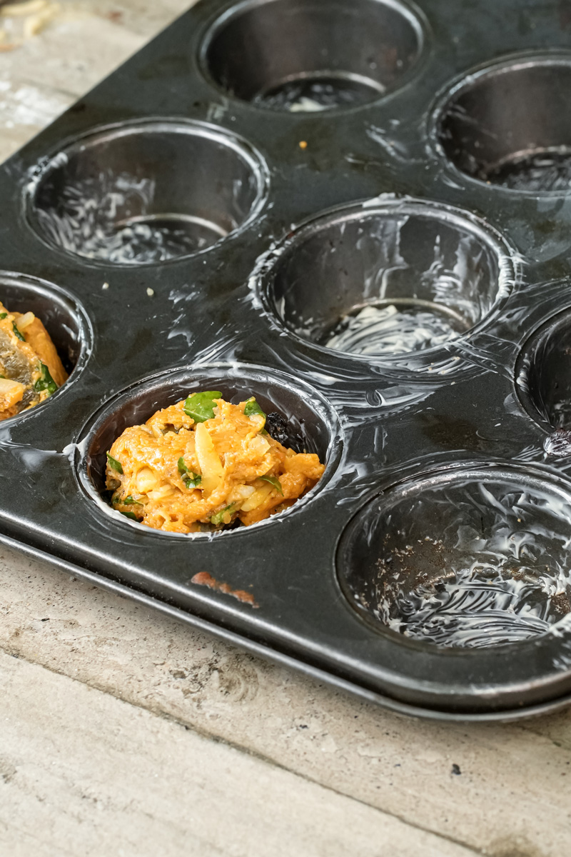 Filling muffin tin with pizza muffin batter using ice cream scoop