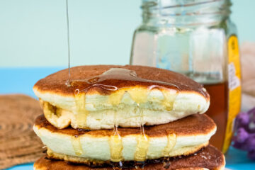 Fluffy Japanese pancakes with honey drizzle stacked on white plate