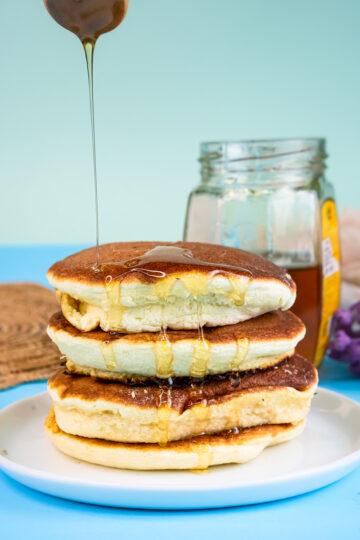 Fluffy Japanese pancakes with honey drizzle stacked on white plate
