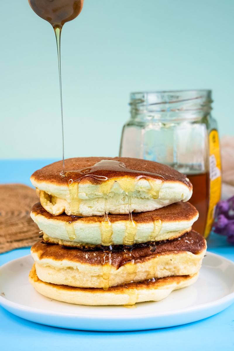Fluffy Japanese pancakes with honey drizzle stacked on white plate