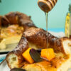 German pancakes with honey drizzle and fresh fruit garnish on white plates