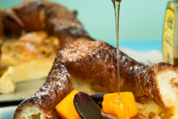 German pancakes with honey drizzle and fresh fruit garnish on white plates