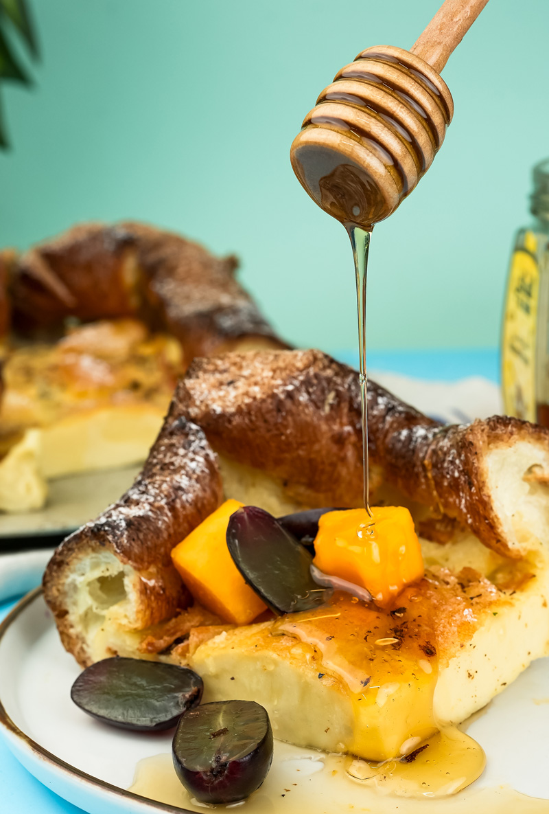 German pancakes with honey drizzle and fresh fruit garnish on white plates